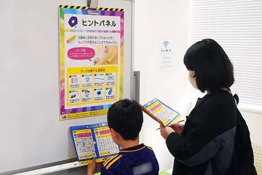 ワークショップの流れの4枚のパネルを回遊しながら防災テーマの謎解きに挑戦している画像