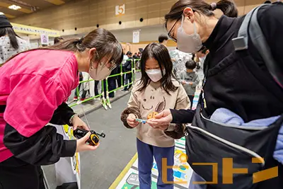 『巨大防災スゴロク』で防災ラジオを体験している親子の様子