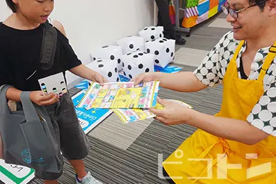 「防災グッズ大賞2025」アイデア賞受賞の『防災スゴロク』を景品として参加した子供にプレゼントしている様子