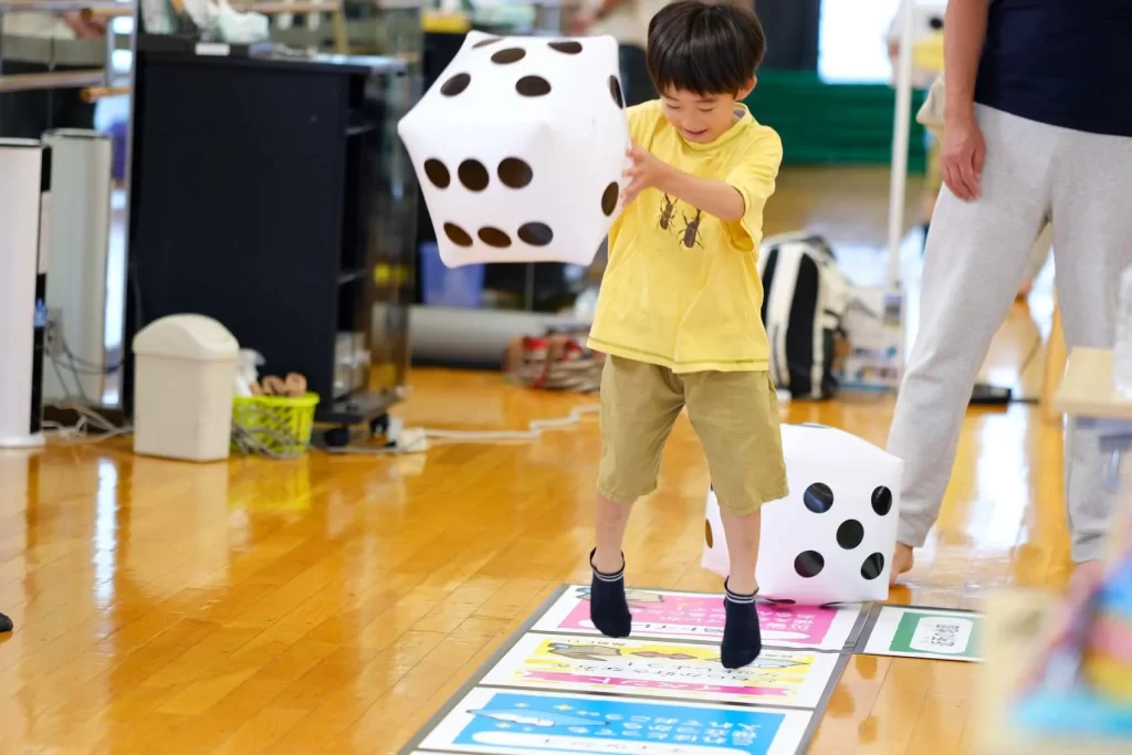 大きなサイコロを持ってジャンプする男の子