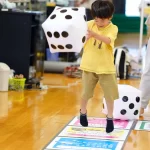 大きなサイコロを持ってジャンプする男の子