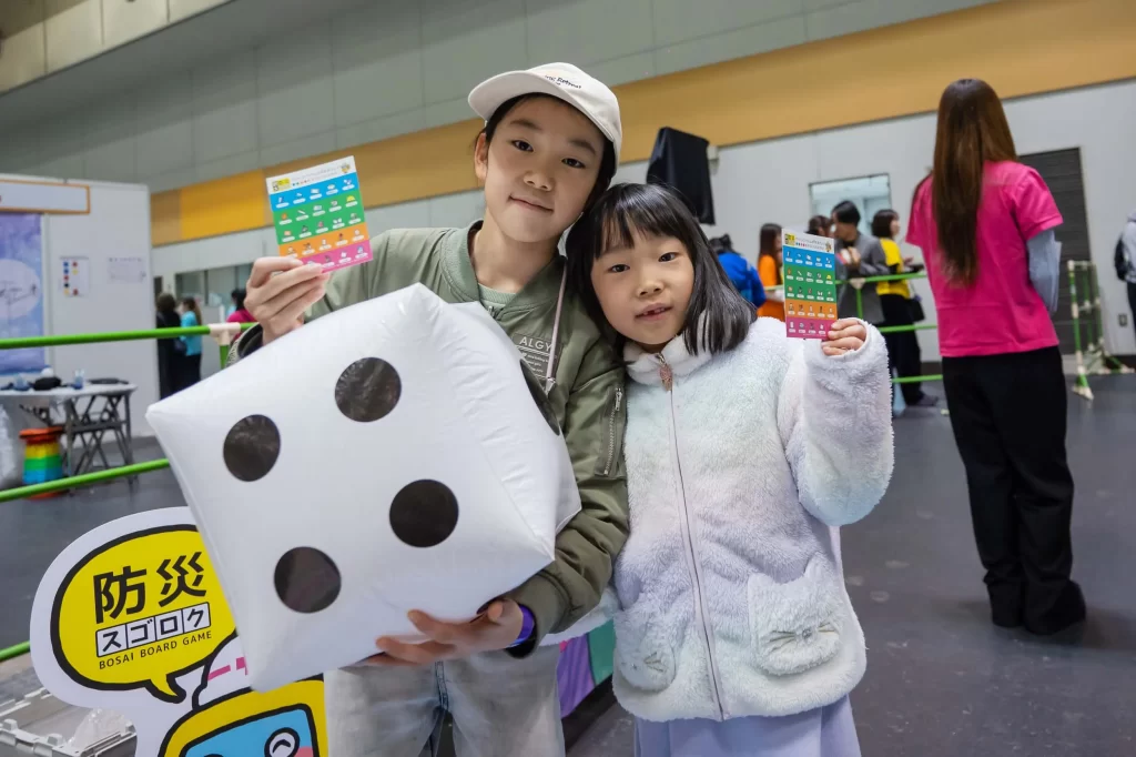 大きなサイコロとビンゴカードを持つ姉妹