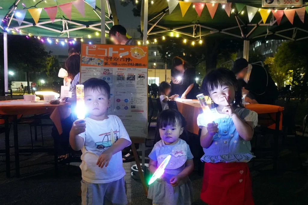 ピコトンの光る工作を持ちポーズをとる子供たち3名