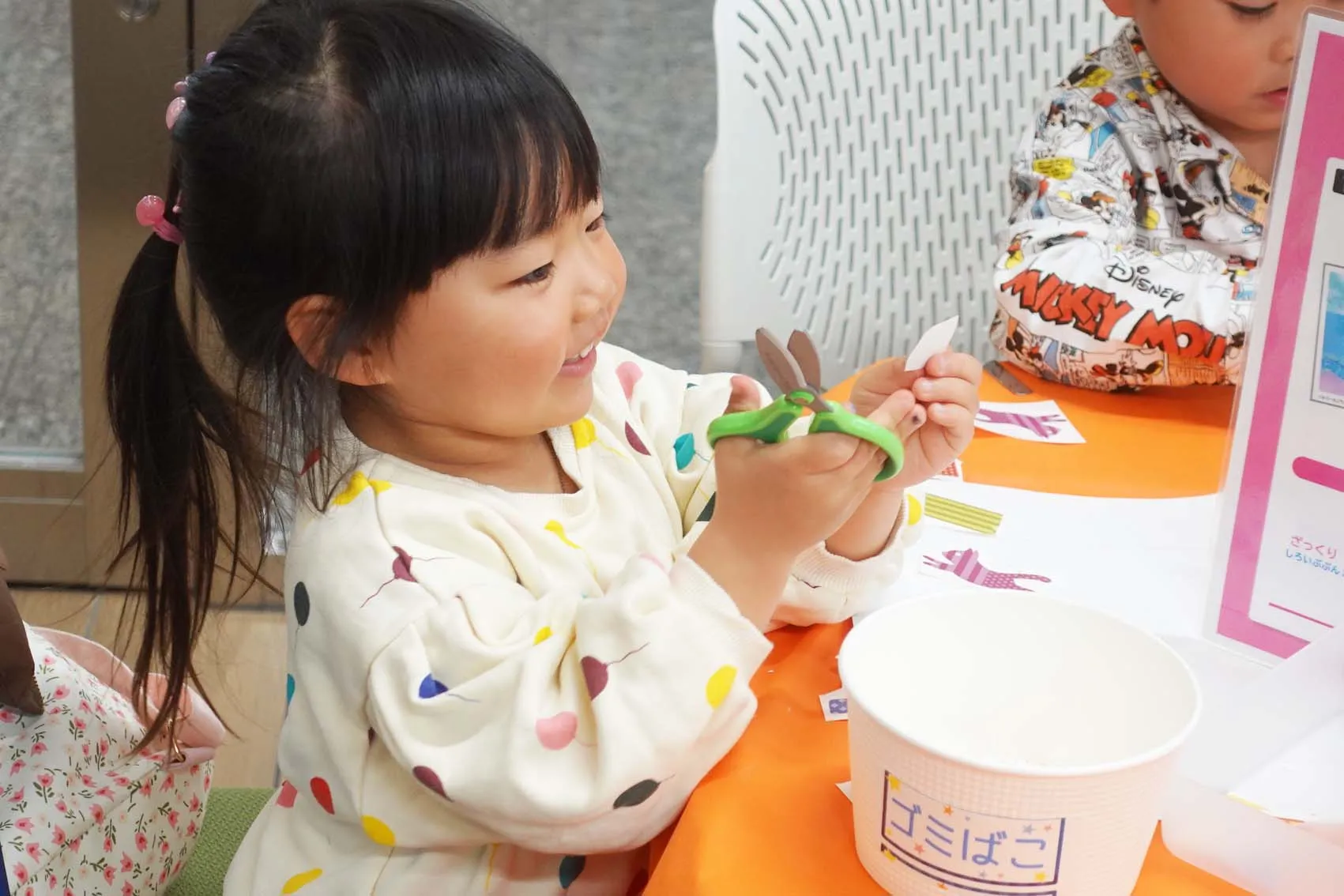 中野区のシェアノマイベントで『つくってタオル』をハサミを使って制作する笑顔の女の子