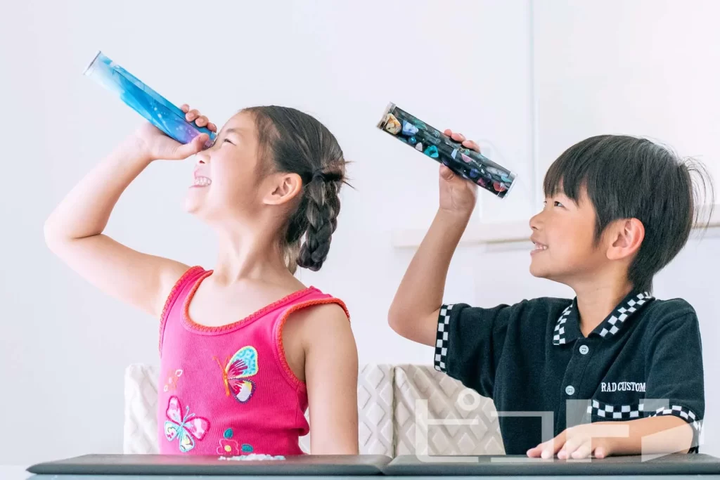 『クリスタル万華鏡』の完成品を覗く女の子と男の子