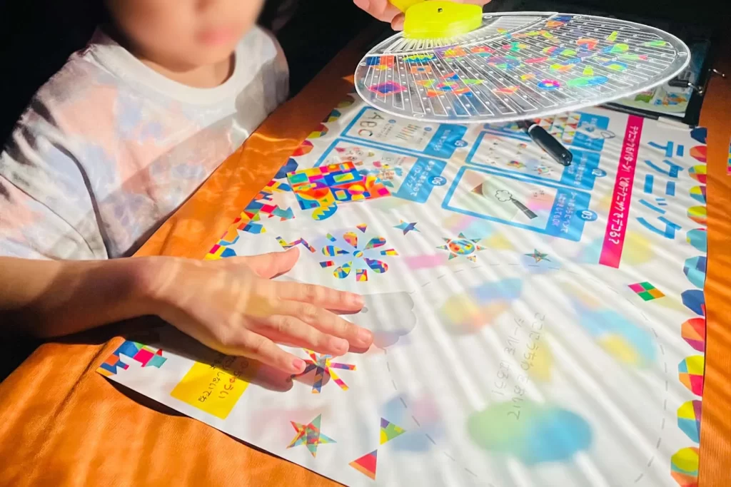 暗いイベント会場で『光る!デコうちわ』を光に透かす男の子