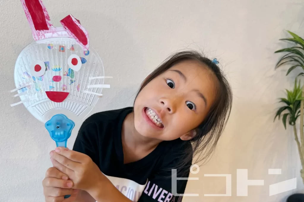 ウサギの耳と顔のついた『光る!デコうちわ』を持ってポーズをとる女の子