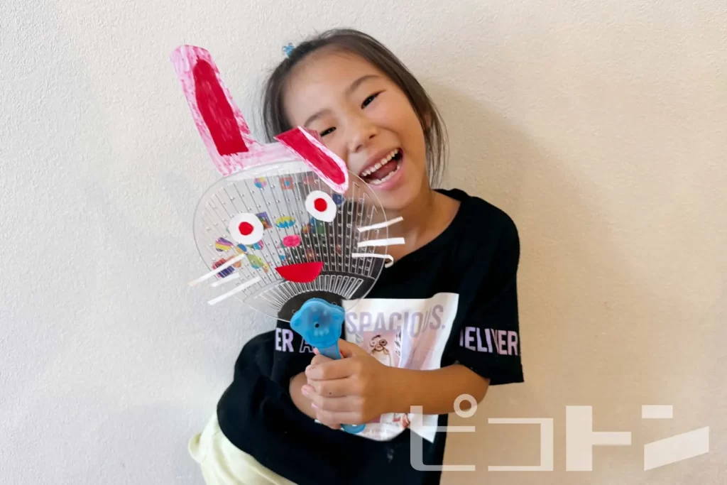 ウサギの耳と顔のついた『光る!デコうちわ』を持ってポーズをとる女の子