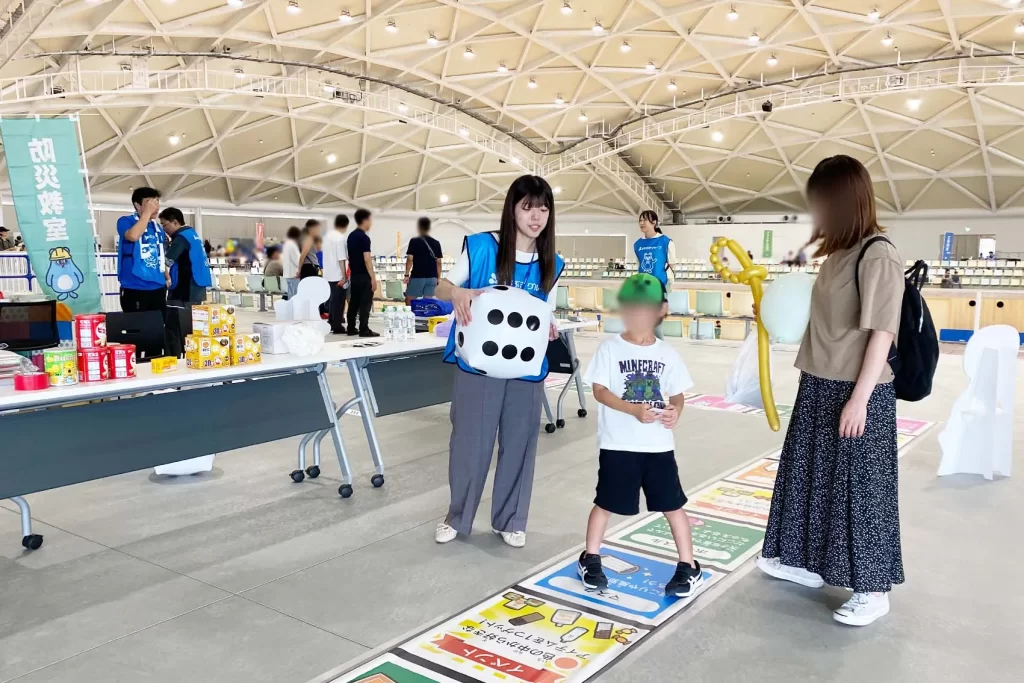 あなぶきハウジングで『巨大防災スゴロク』を体験するスタッフと男の子
