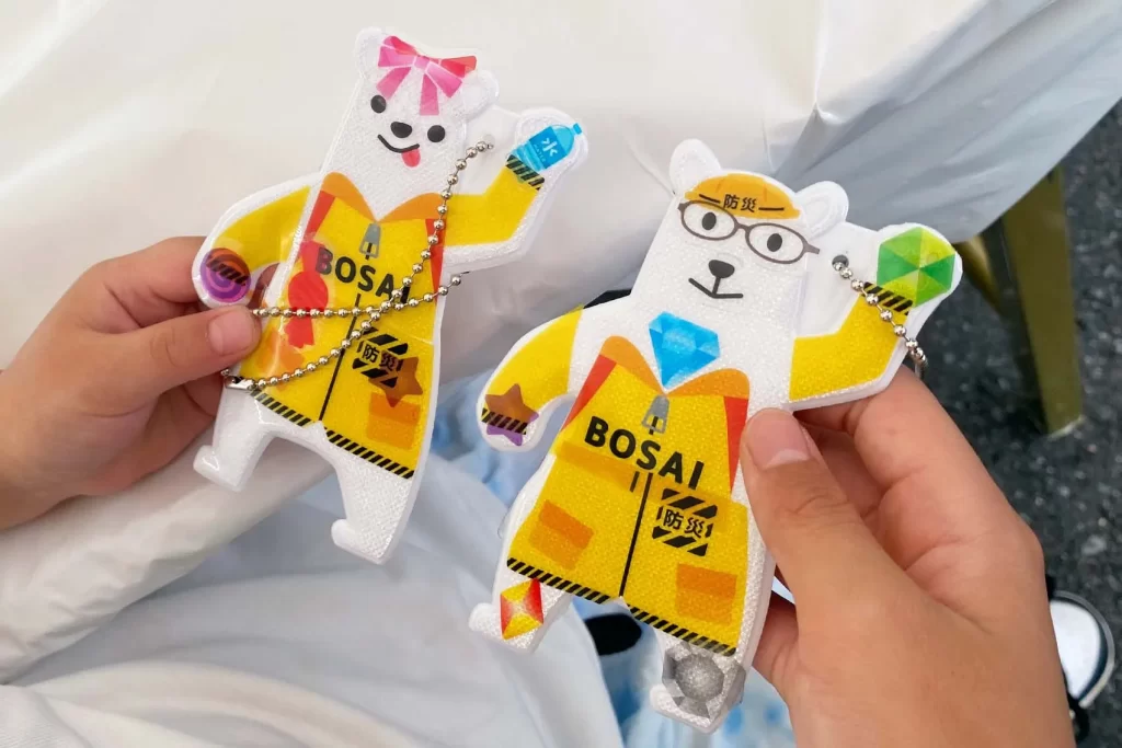 東京ガスライフバル足立で開催した『ピカッと！安全キーホルダー』の完成品2つを持つ兄妹