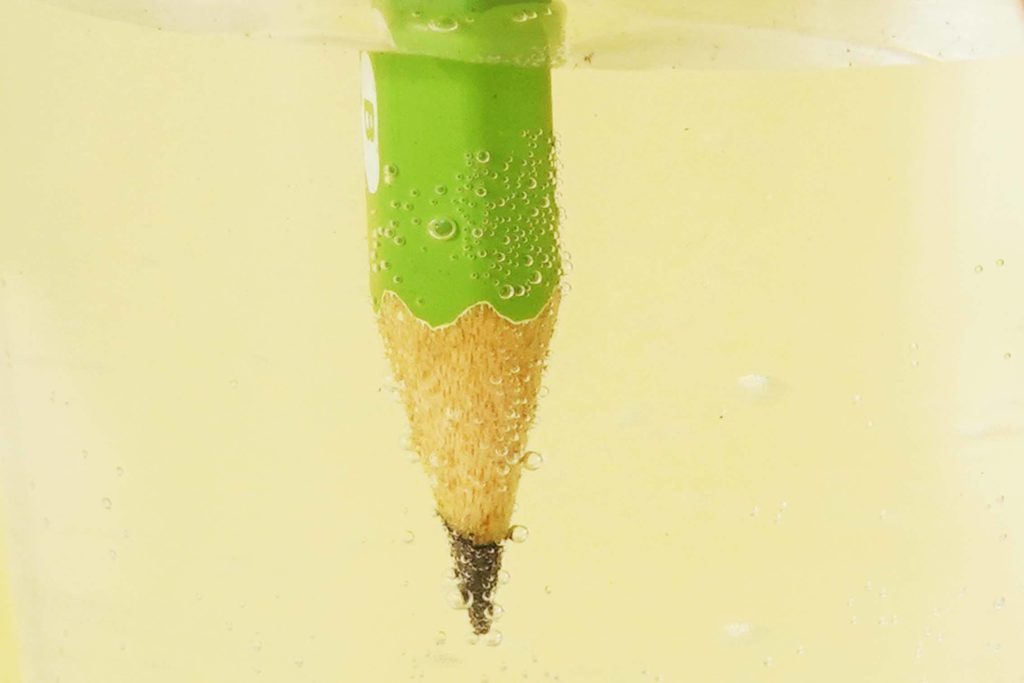 電気分解をして水中の鉛筆に酸素が発生する様子