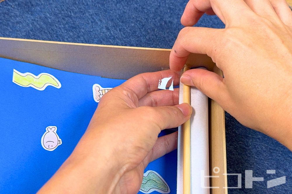 割り箸と折り紙をテープで貼っている