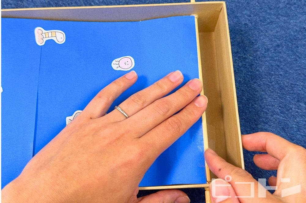 折り紙をテープで貼っている