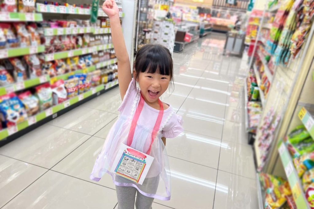 スーパーマーケットの中で「お買い物ビンゴ」を首にぶら下げている女の子