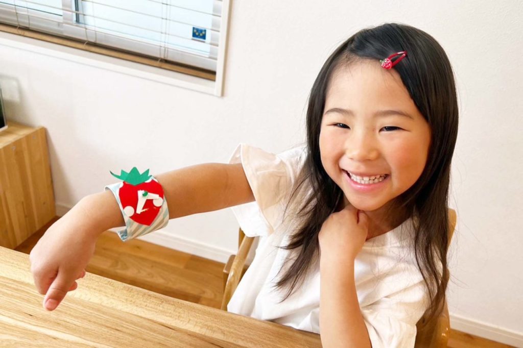 100均の材料で作った「イチゴ時計」を腕につけて笑っている女の子