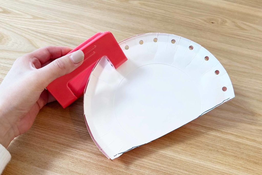 穴あけパンチを使い紙皿にの外側に穴を開ける様子