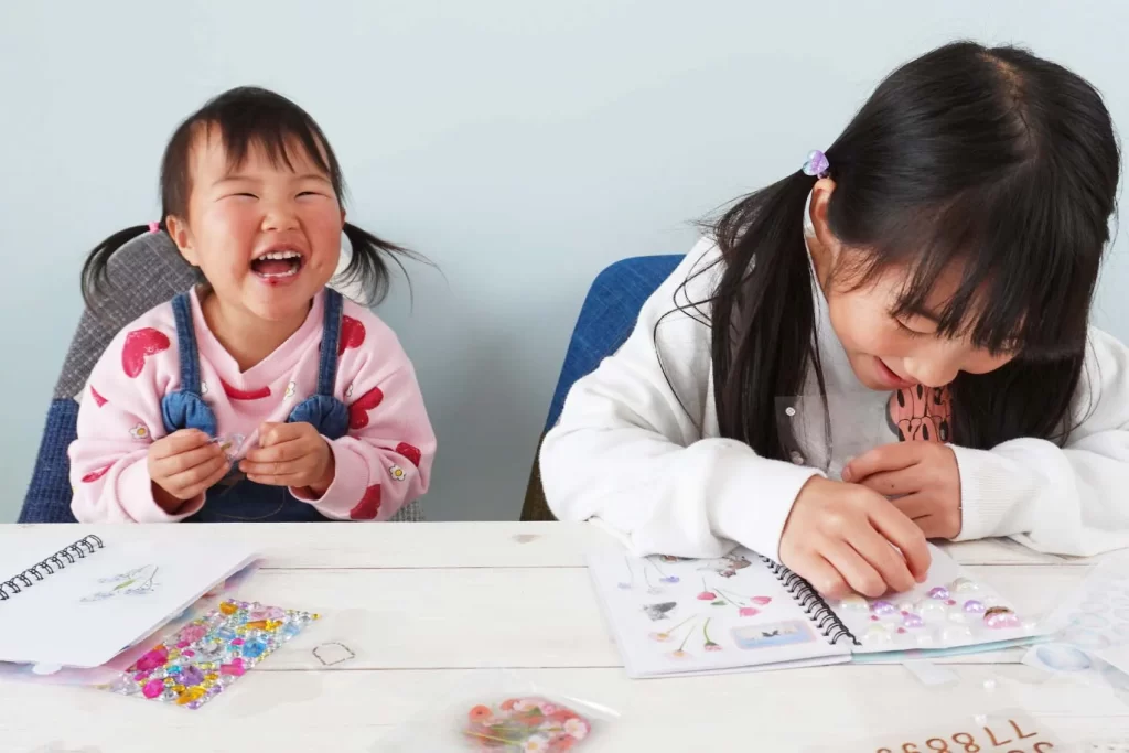 子どもたちが100均のシール帳にシールを貼っている様子