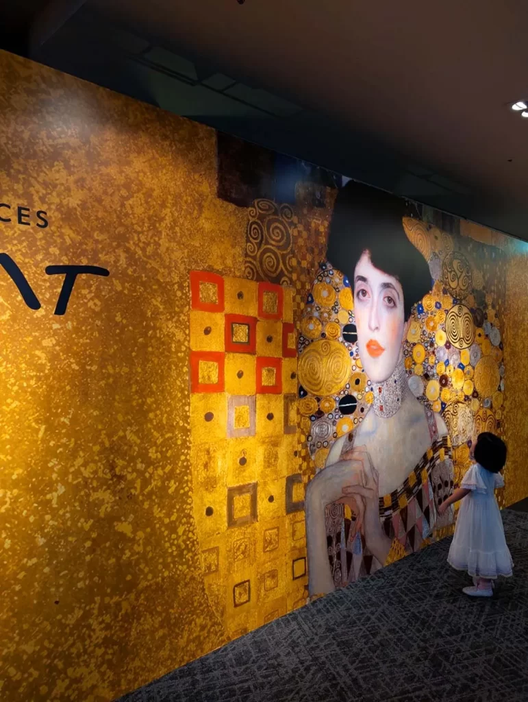 クリムト・アライブ 東京展の入口で壁面を見上げる女の子
