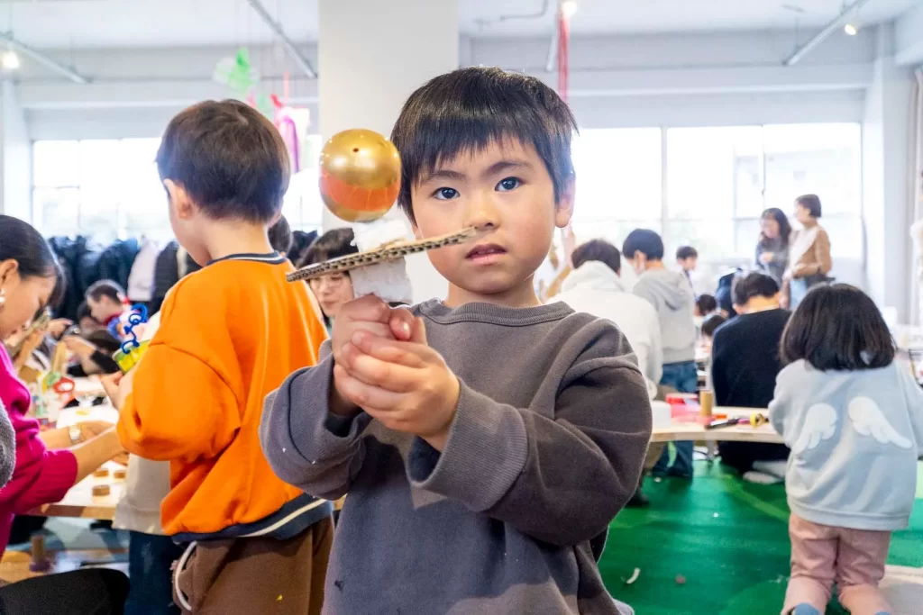 金のカプセルを使った作品を持つ男の子