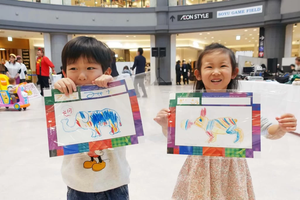 『うごく!シャッフルぬりえ』の完成品を持つ男の子と女の子