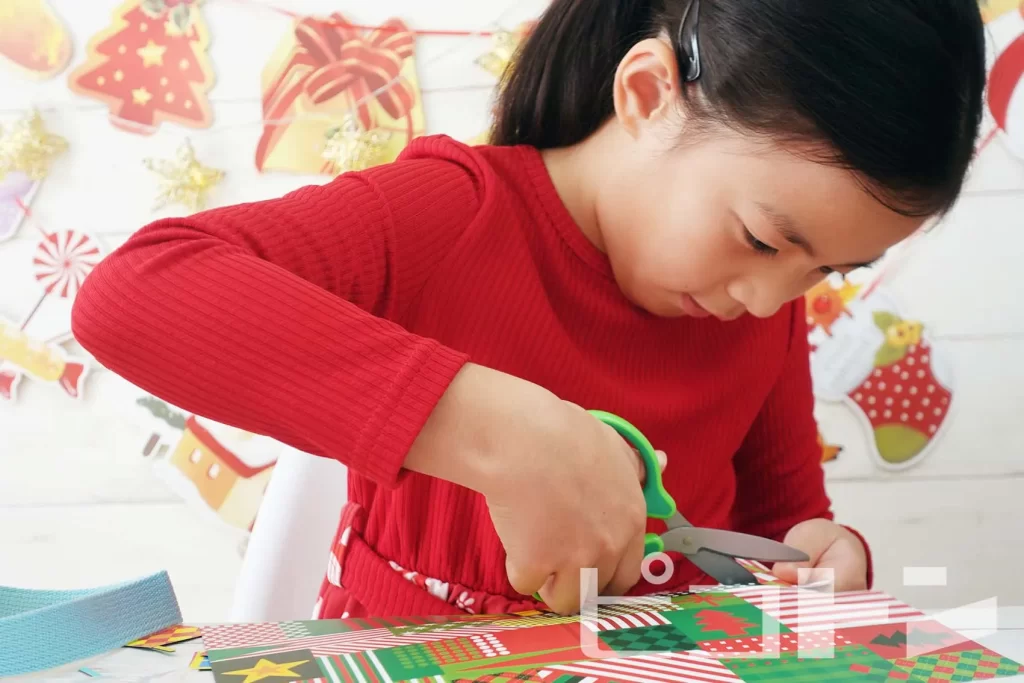 『Myおうちバッグクリスマスver.』の工作をする女の子(シートをハサミで切る様子)