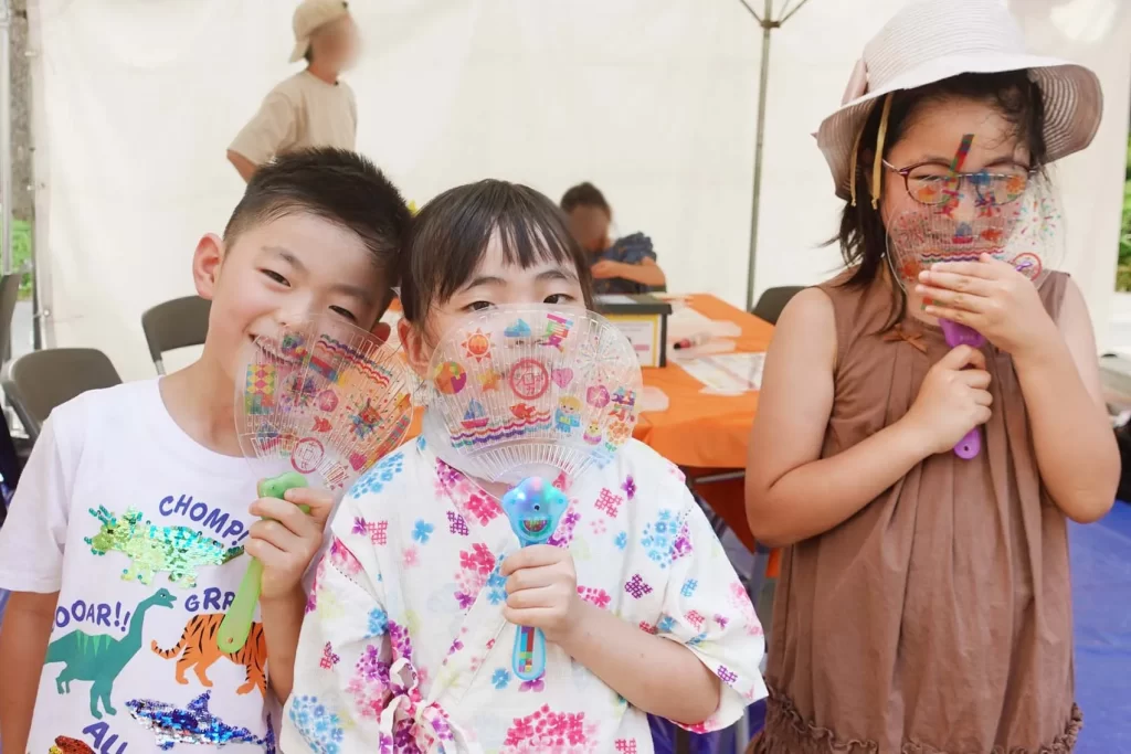 ナカボン2025の『光る!デコうちわ』の完成品を持つ子ども3名