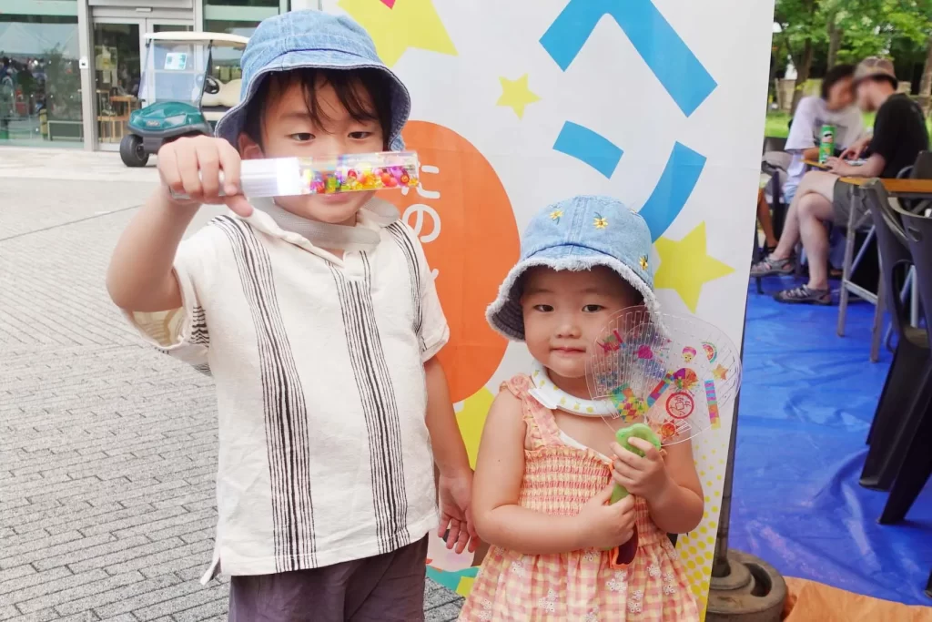 ナカボンver.の『光る!ウォータースティックライト』と『光る!デコうちわ』を持つ男の子と女の子