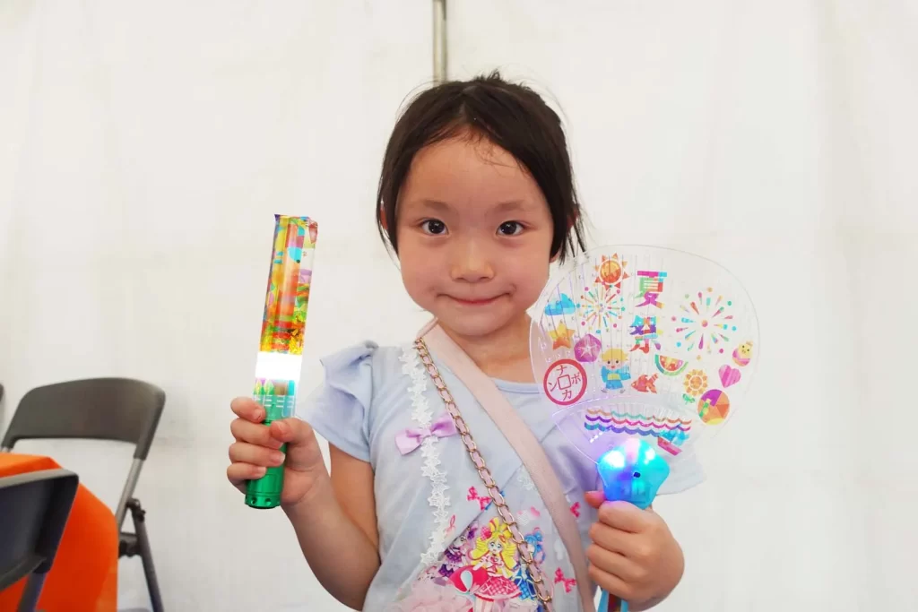 ナカボンver.の『光る!ウォータースティックライト』と『光る!デコうちわ』を持つ女の子