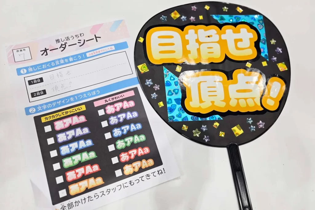 「目指せ頂点」と書かれた推し活うちわ
