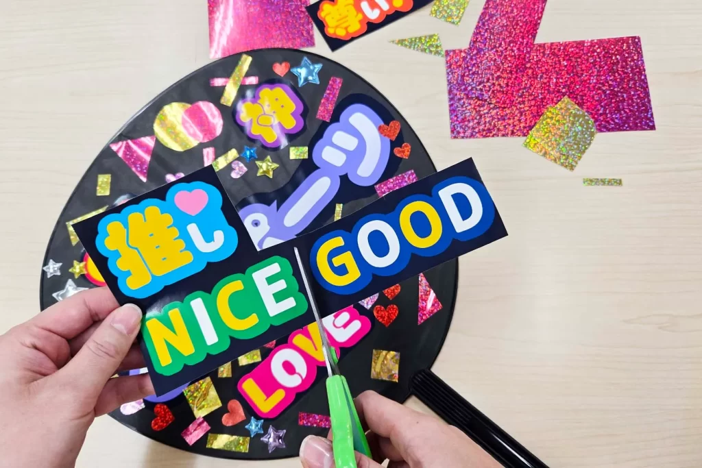 シールをカットしてうちわに貼る様子