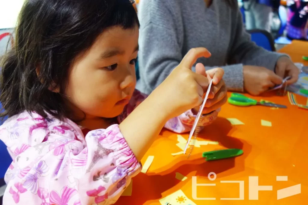 東芝未来科学館で行われた工作イベント『TOSHIBAキラキラリフレクター』にシールを貼る女の子