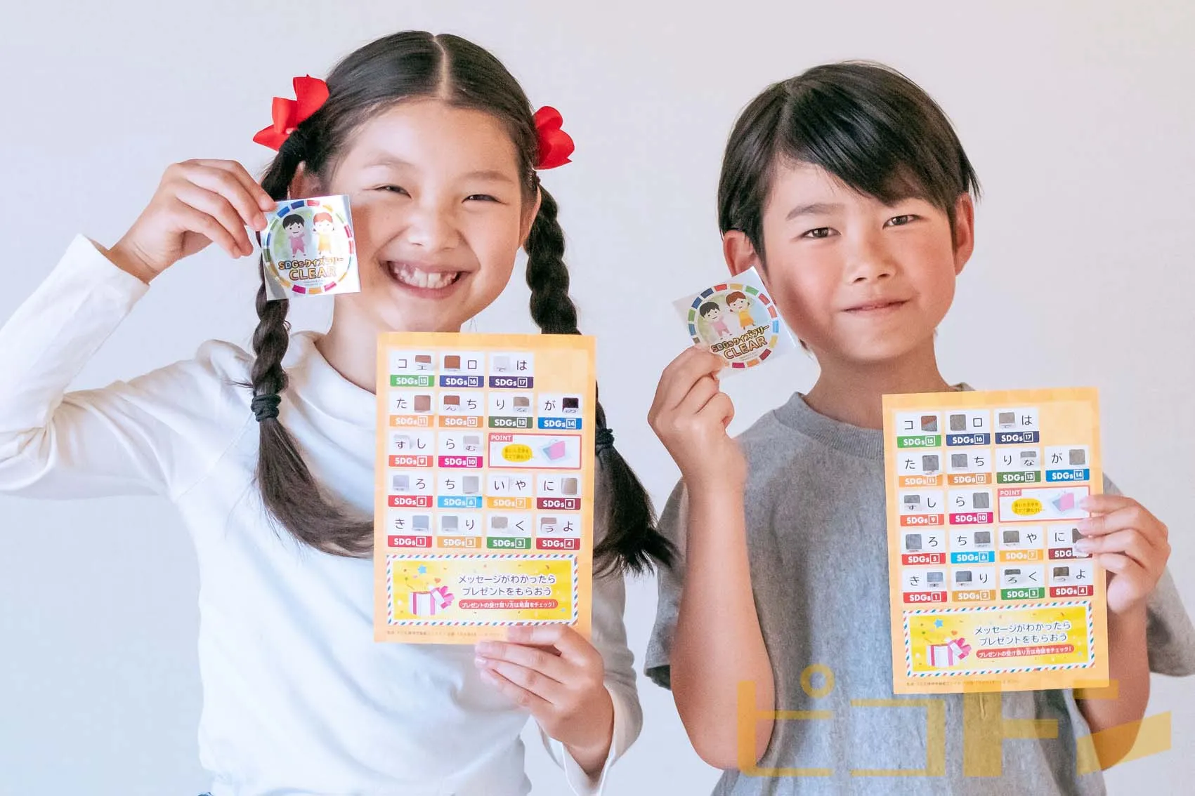 SDGsクイズラリーのカードとシールを持つ女の子と男の子