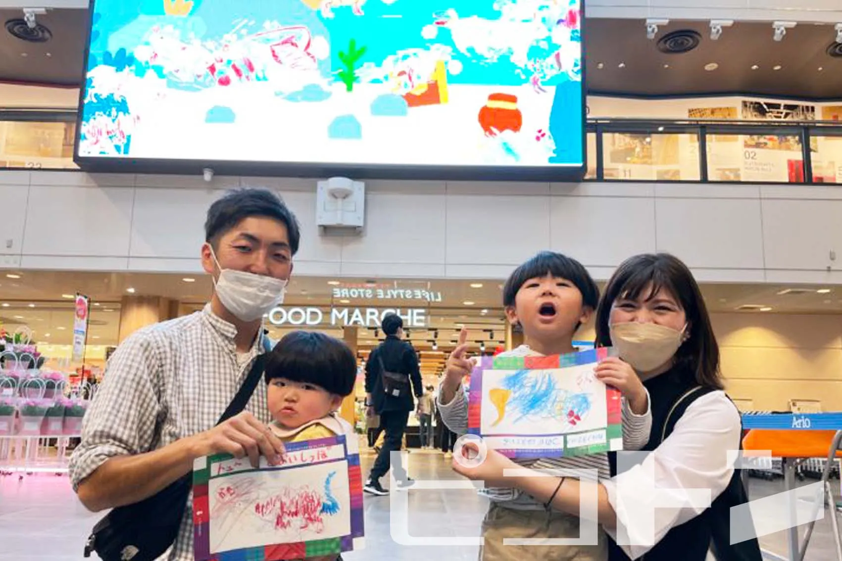 『うごく!シャッフルぬりえ』のモニターの前で記念撮影する家族