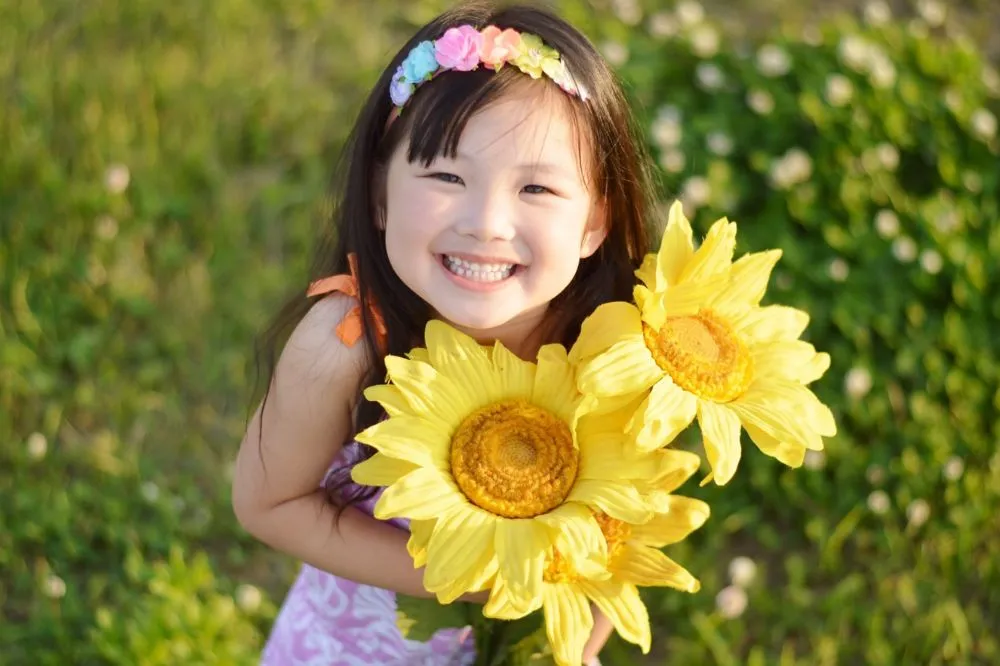 夏といえば? 行事やアイデア22選を紹介する記事の向日葵を持った女の子の写真