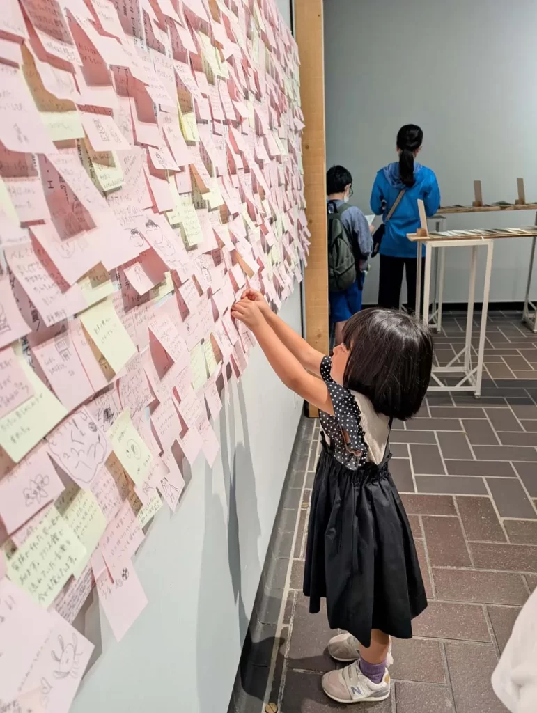 東京都美術館「つくるよろこび 生きるためのDIY」で付箋の作品に触れる女の子