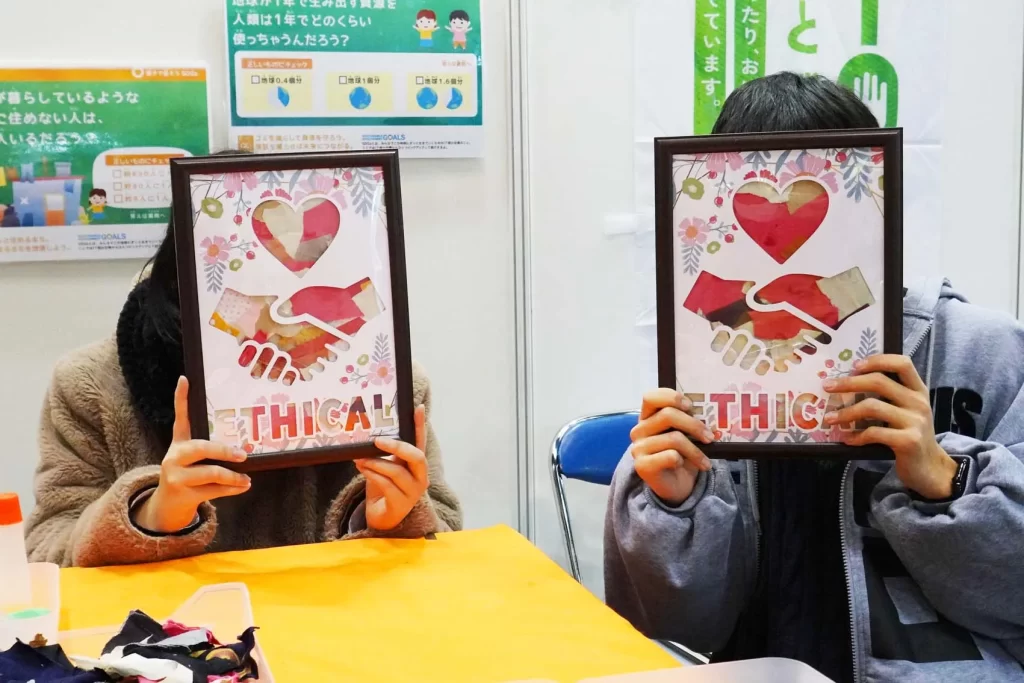 エコプロ2025で実施した「アップサイクル・ウォールアート」の完成品を持つ2名