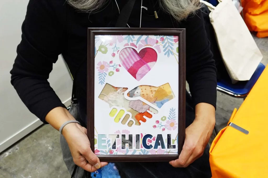 エコプロ2025で実施した「アップサイクル・ウォールアート」の完成品を持つ女性