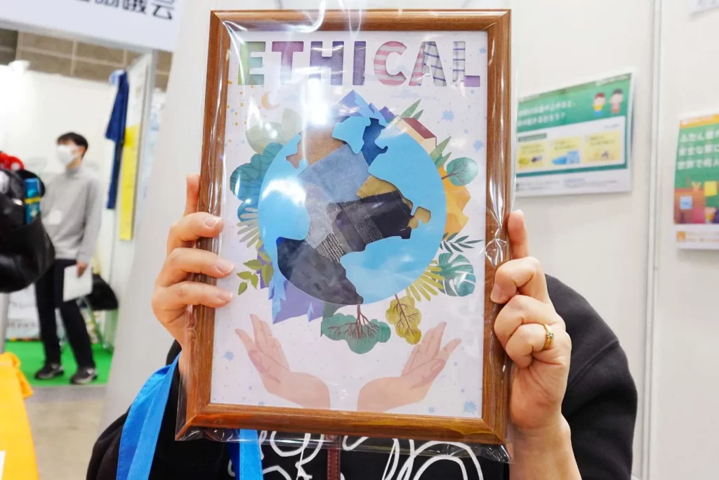 エコプロ2025で実施した「アップサイクル・ウォールアート」の完成品を持つ参加者の女性