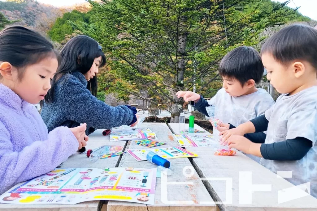 キャンプ場で『光る! ウォータースティックライト』工作する子供4人〈1〉